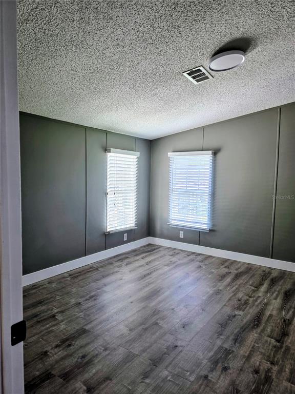 An empty room with gray paneled walls, white trim, and wood-look flooring — 205 W SHELL POINT ROAD Bldg A, RUSKIN, FL