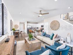 An open-concept living room and kitchen featuring light wood floors, a ceiling fan, and furniture — 4519 TRINITY WAY UNIT TH-C3, KISSIMMEE, FL