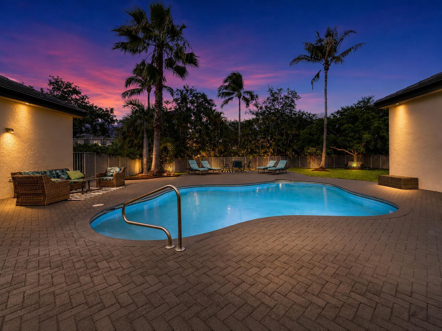 A kidney-shaped swimming pool sits on a paved patio between two house wings at sunset — 6569 NW 103rd Terrace, Parkland FL 33076, PARKLAND, FL