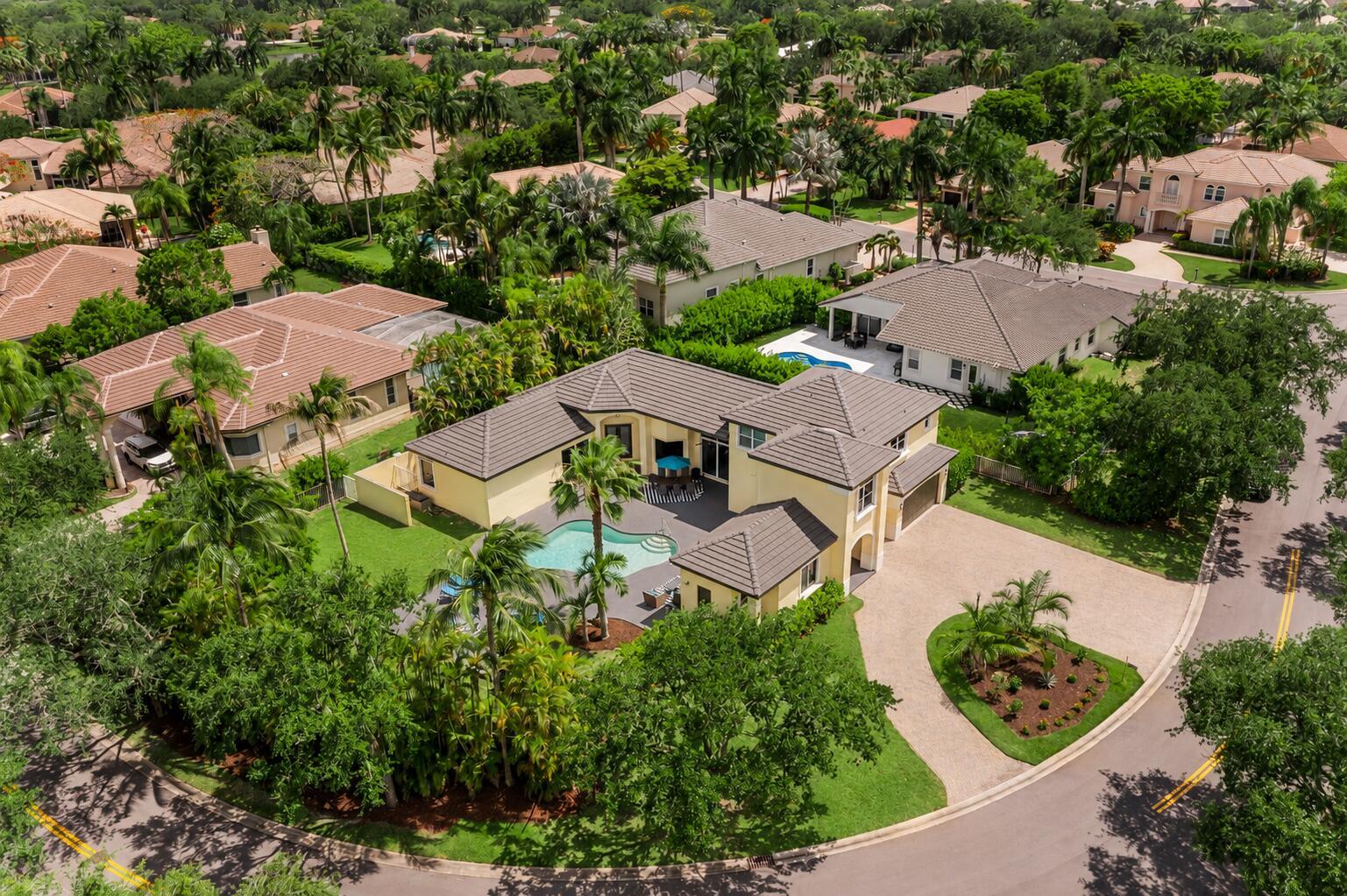 An aerial view of a yellow house with a tile roof, pool, and circular driveway — 6569 NW 103rd Terrace, Parkland FL 33076, PARKLAND, FL