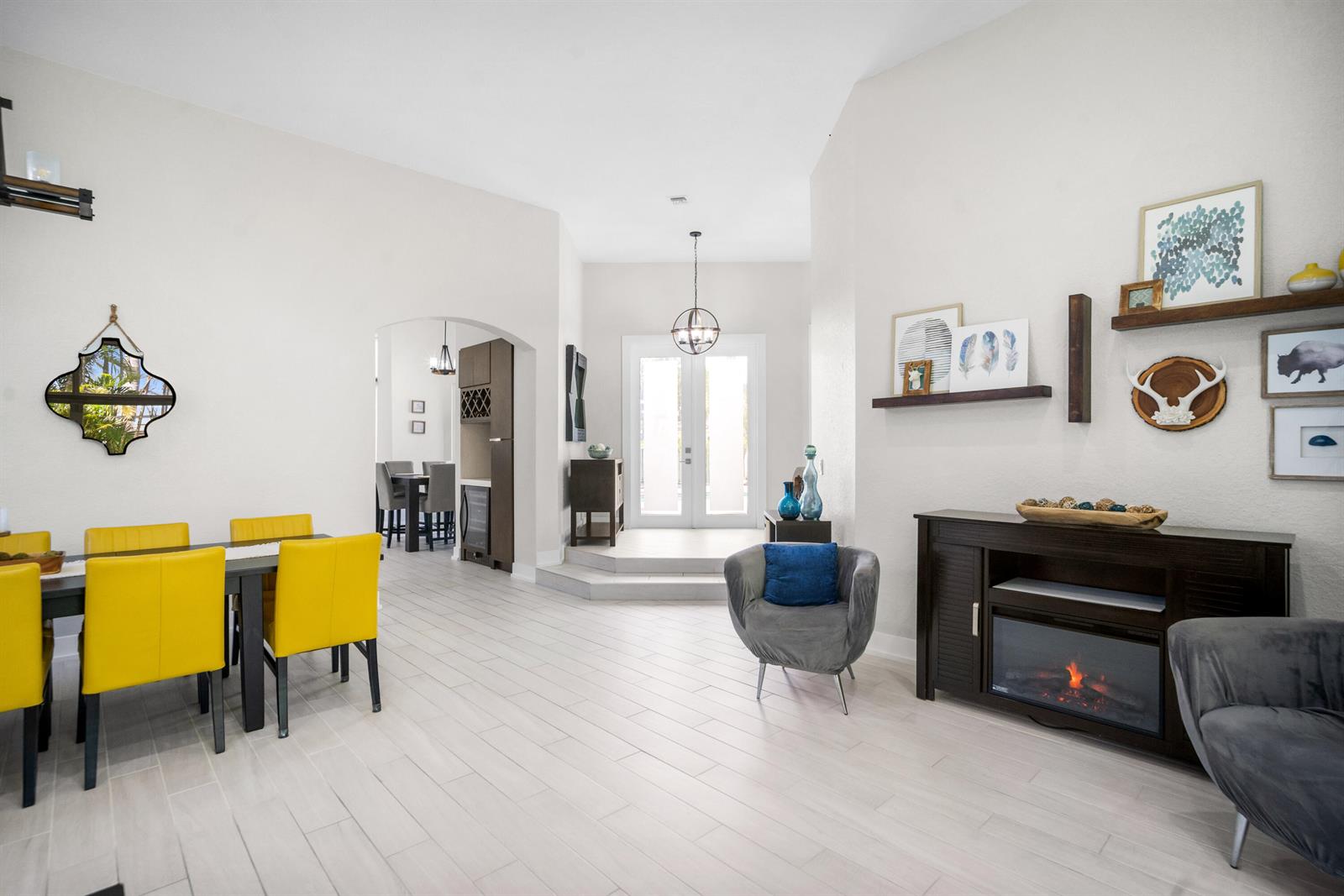 A dining area and living space feature light wood floors, yellow chairs, and a fireplace — 6569 NW 103rd Terrace, Parkland FL 33076, PARKLAND, FL