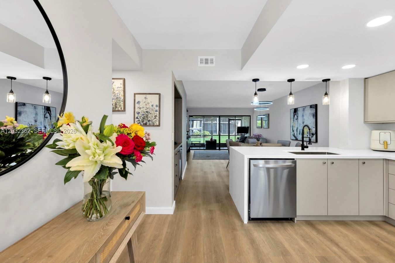 A modern kitchen with light cabinetry and stainless steel appliances opens into a living area — 1929 SW 15th St # 39, Deerfield Beach FL 33442, DEERFIELD BEACH, FL