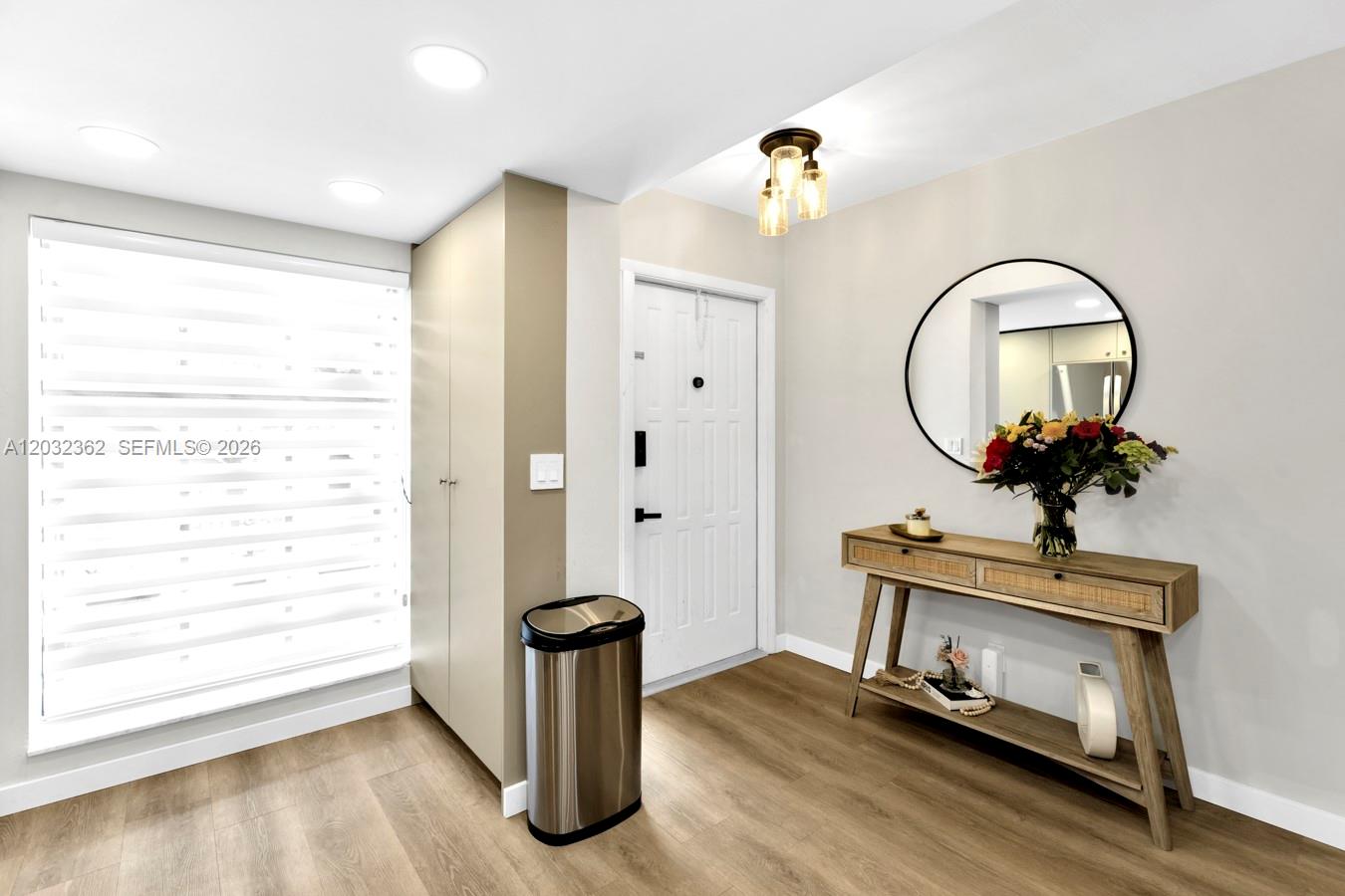 An entryway features a console table, a round mirror, a tall cabinet, and wood-look flooring — 1929 SW 15th St # 39, Deerfield Beach FL 33442, DEERFIELD BEACH, FL