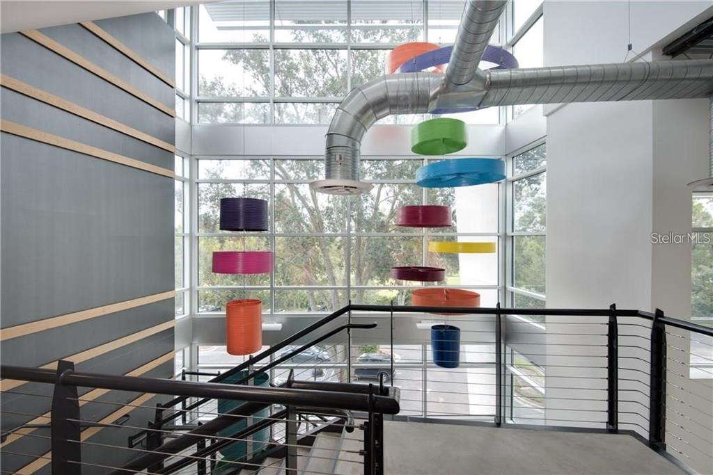 A staircase landing features a metal railing and colorful hanging cylindrical light fixtures — 429 S KELLER ROAD UNIT 310, ORLANDO, FL