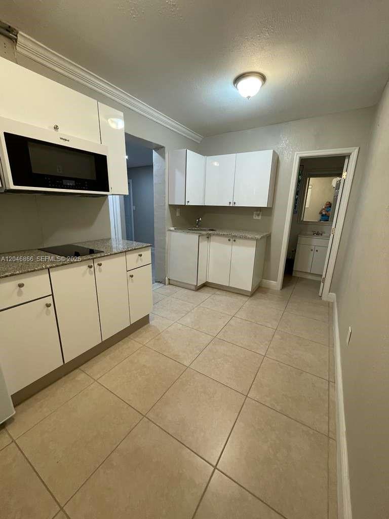 A kitchen features white cabinets, granite countertops, a built-in microwave, and light-colored tile flooring — 11730 SW 172nd St # 0, Miami FL 33177, MIAMI, FL