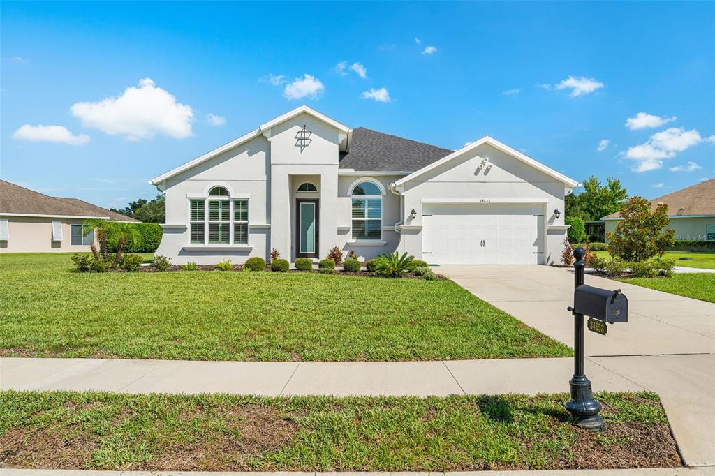 A single-story house with a white stucco exterior, a two-car garage, and a front lawn — 34653 HEAVENLY LANE, DADE CITY, FL