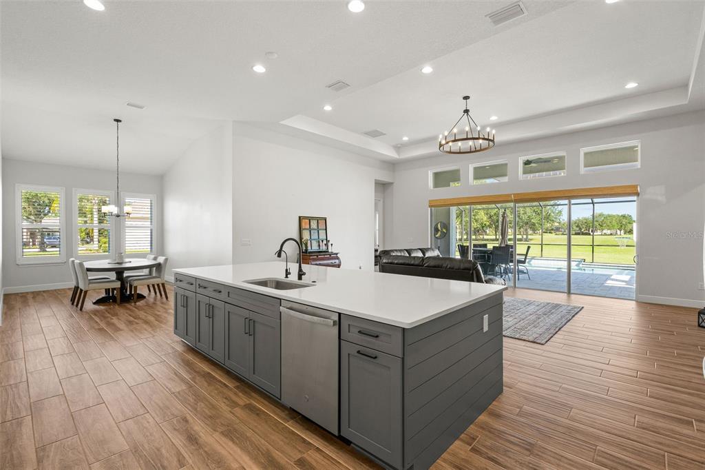 A kitchen island with gray cabinets and white countertops overlooks a living area and pool — 34653 HEAVENLY LANE, DADE CITY, FL