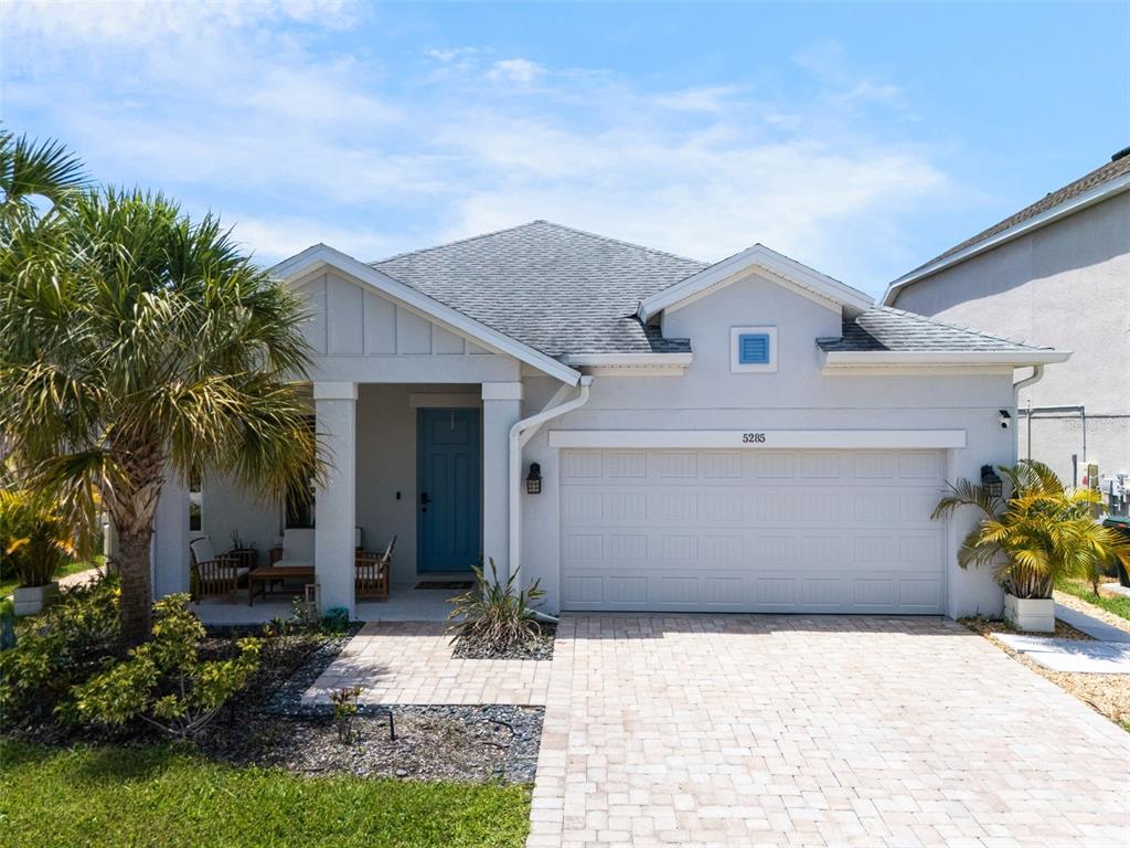 A single-story house with a blue front door, a two-car garage, and a paver driveway — 5285 TWINFLOWER LANE, SARASOTA, FL