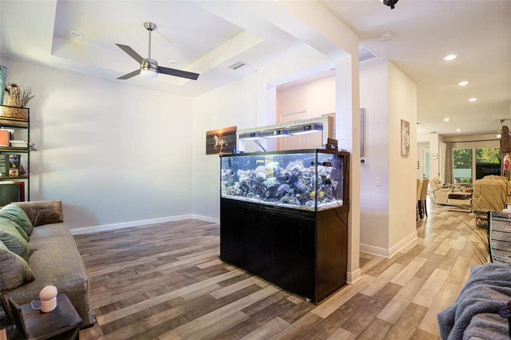 A living room features a large saltwater aquarium, wood-look flooring, and a tray ceiling — 5285 TWINFLOWER LANE, SARASOTA, FL