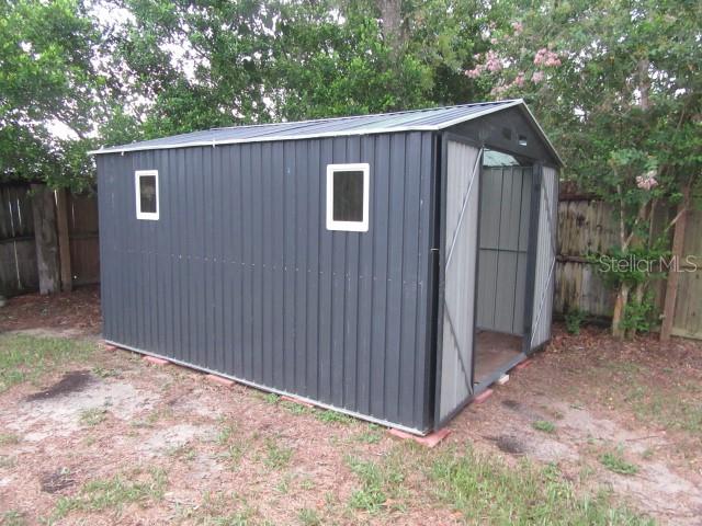 A dark gray metal storage shed with two windows sits on a grassy lot — 2088 BOLGER AVENUE, SPRING HILL, FL