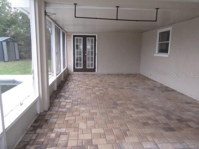 A covered patio features paver flooring, a screen enclosure, and double doors leading inside — 2088 BOLGER AVENUE, SPRING HILL, FL