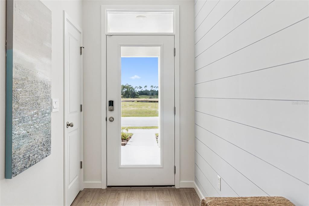 An entryway features a white door with a glass panel, shiplap walls, and wood flooring — 5163 NICKERBEAN STREET, APOPKA, FL