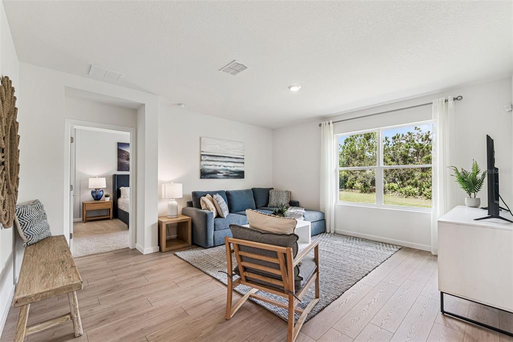 A living room features a blue sectional sofa, a wood-framed chair, and light wood flooring — 5163 NICKERBEAN STREET, APOPKA, FL