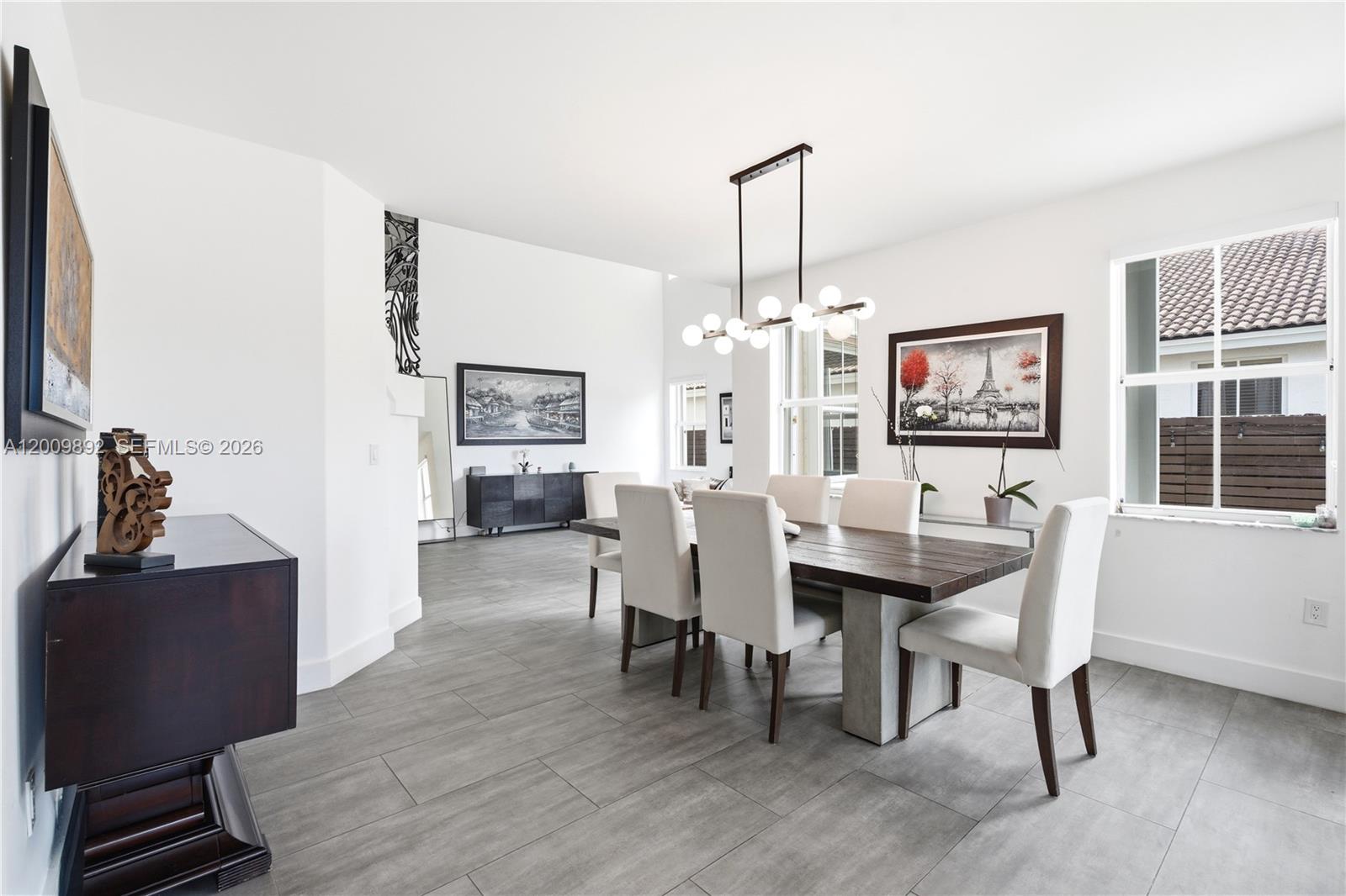 A dining room features a dark wood table, white chairs, and gray tile flooring — 11090 NW 84th St, Doral FL 33178, DORAL, FL