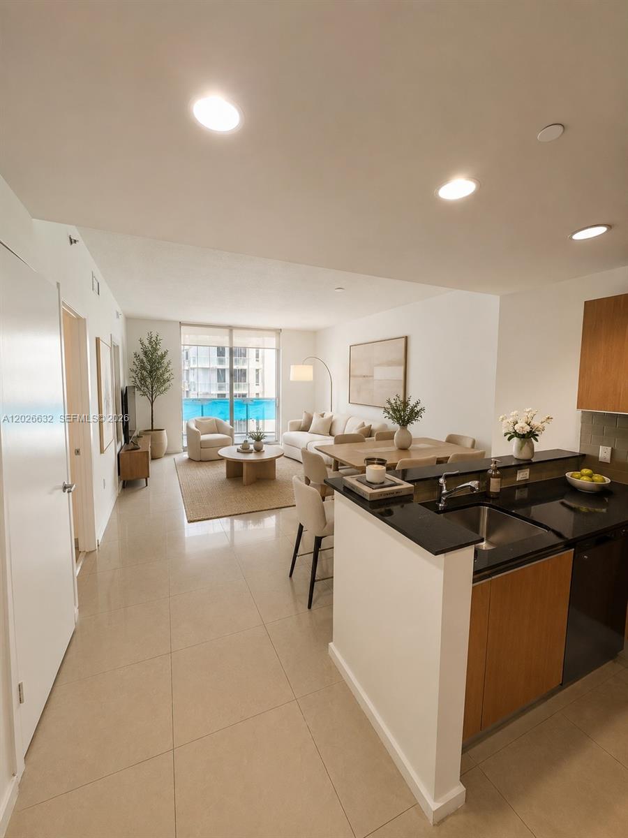 This open-concept living and dining area features tile flooring, a kitchen island, and balcony access — 1060 Brickell Ave # 3915, Miami FL 33131, MIAMI, FL