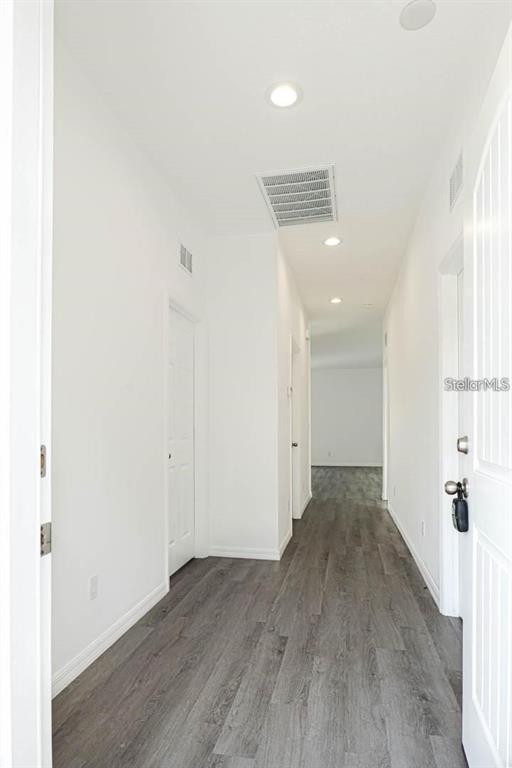 A bright hallway features white walls, recessed lighting, and gray wood-look flooring — 561 WILDMER ROAD SW, PALM BAY, FL