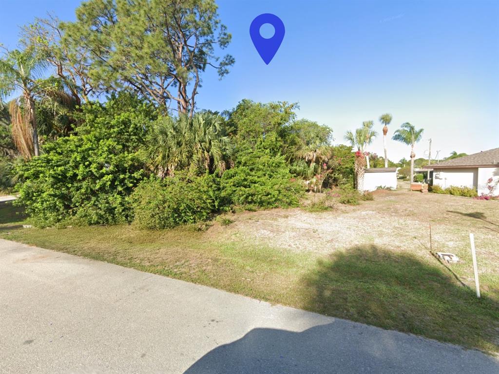 A vacant, overgrown residential lot with trees and shrubs sits next to a suburban house — 4203 DAY STREET, PORT CHARLOTTE, FL
