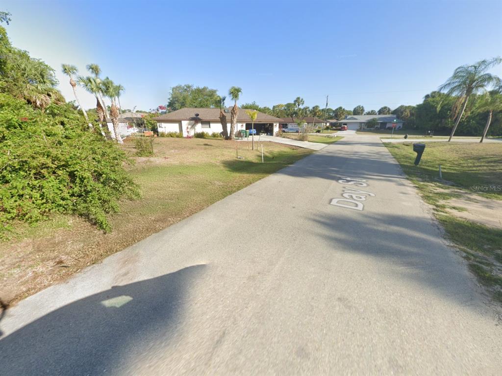 A paved street leads toward a single-story house with palm trees in the front yard — 4203 DAY STREET, PORT CHARLOTTE, FL