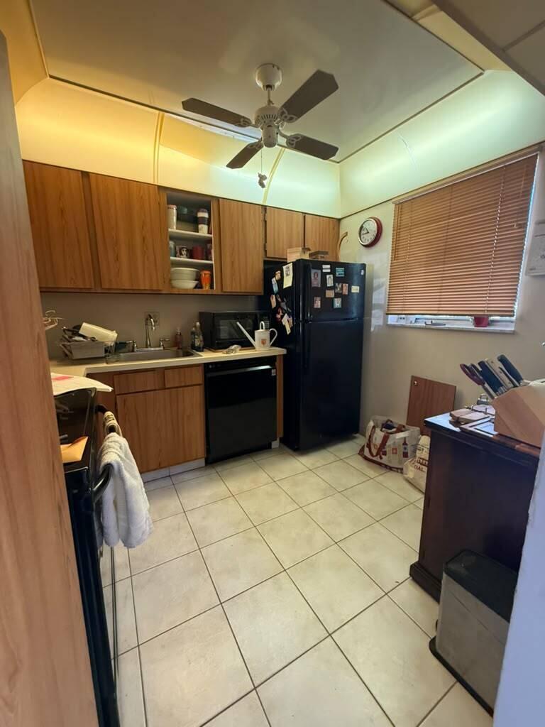 A kitchen with wood cabinets, black appliances, tile flooring, and a ceiling fan — 3210 Holiday Springs Boulevard # 103, Margate FL 33063, MARGATE, FL