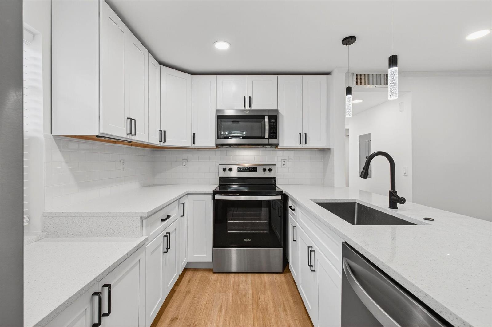 A modern kitchen features white cabinets, stainless steel appliances, quartz countertops, and a black faucet — 449 Normandy J, Delray Beach FL 33484, DELRAY BEACH, FL