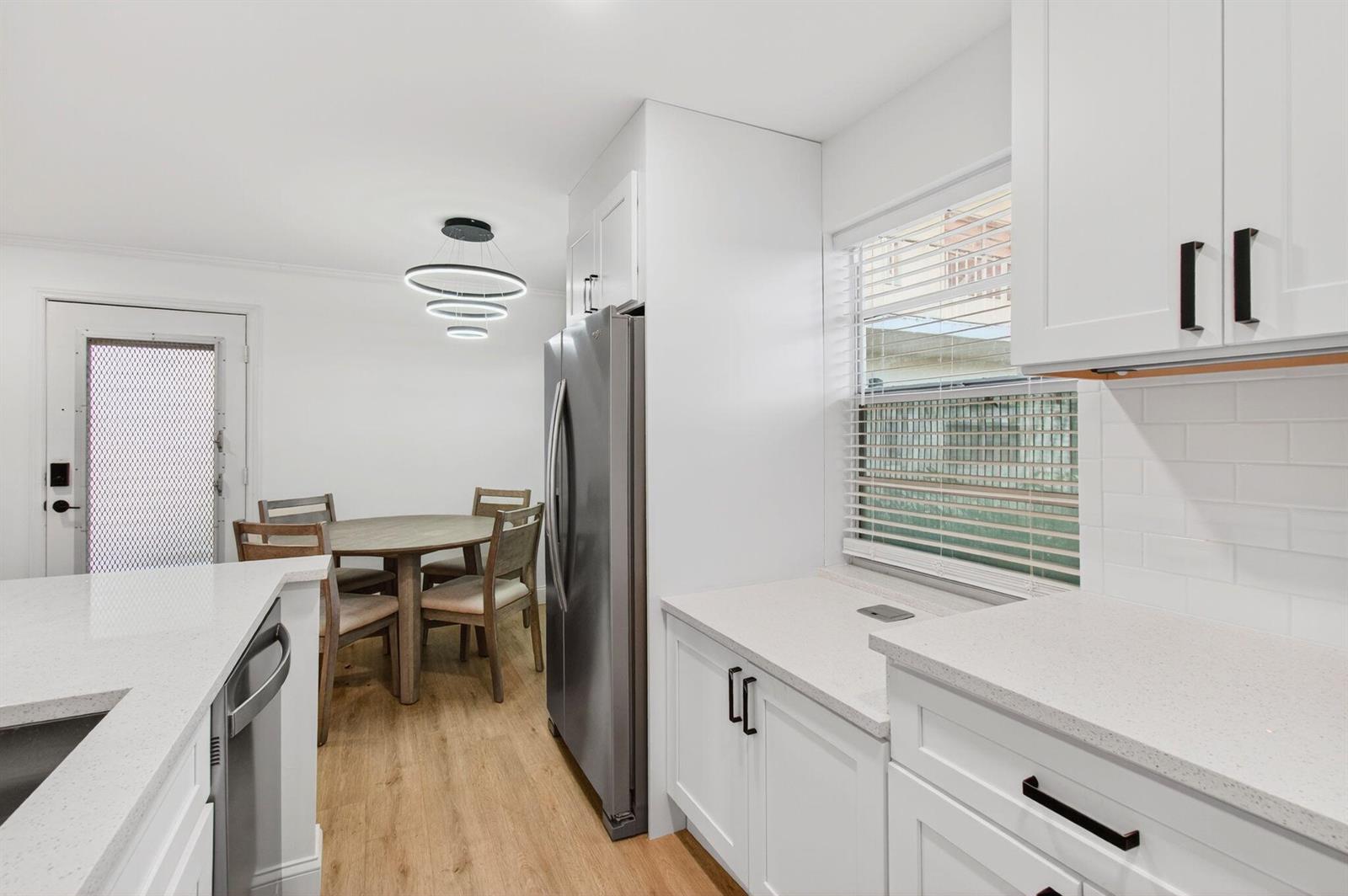 A kitchen with white cabinets, quartz countertops, and a dining area with a round table — 449 Normandy J, Delray Beach FL 33484, DELRAY BEACH, FL