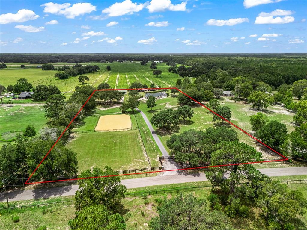An aerial view shows a rural property with a house, riding arena, and fenced pastures — 14356 SW 101ST LANE, DUNNELLON, FL