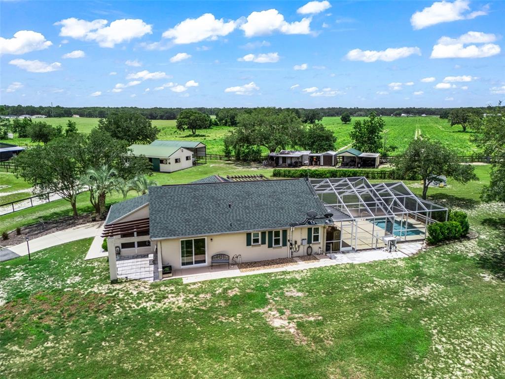 An aerial view of a house with a pool enclosure and several outbuildings on land — 14356 SW 101ST LANE, DUNNELLON, FL