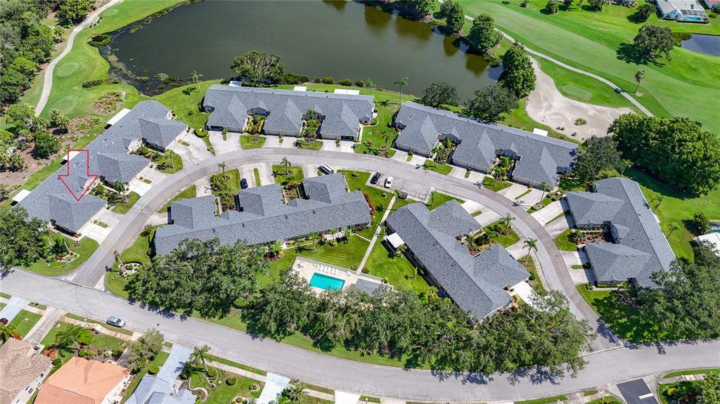 An aerial view shows a residential complex with gray roofs, a pool, and a pond — 6948 STONEYWALK COURT, BRADENTON, FL