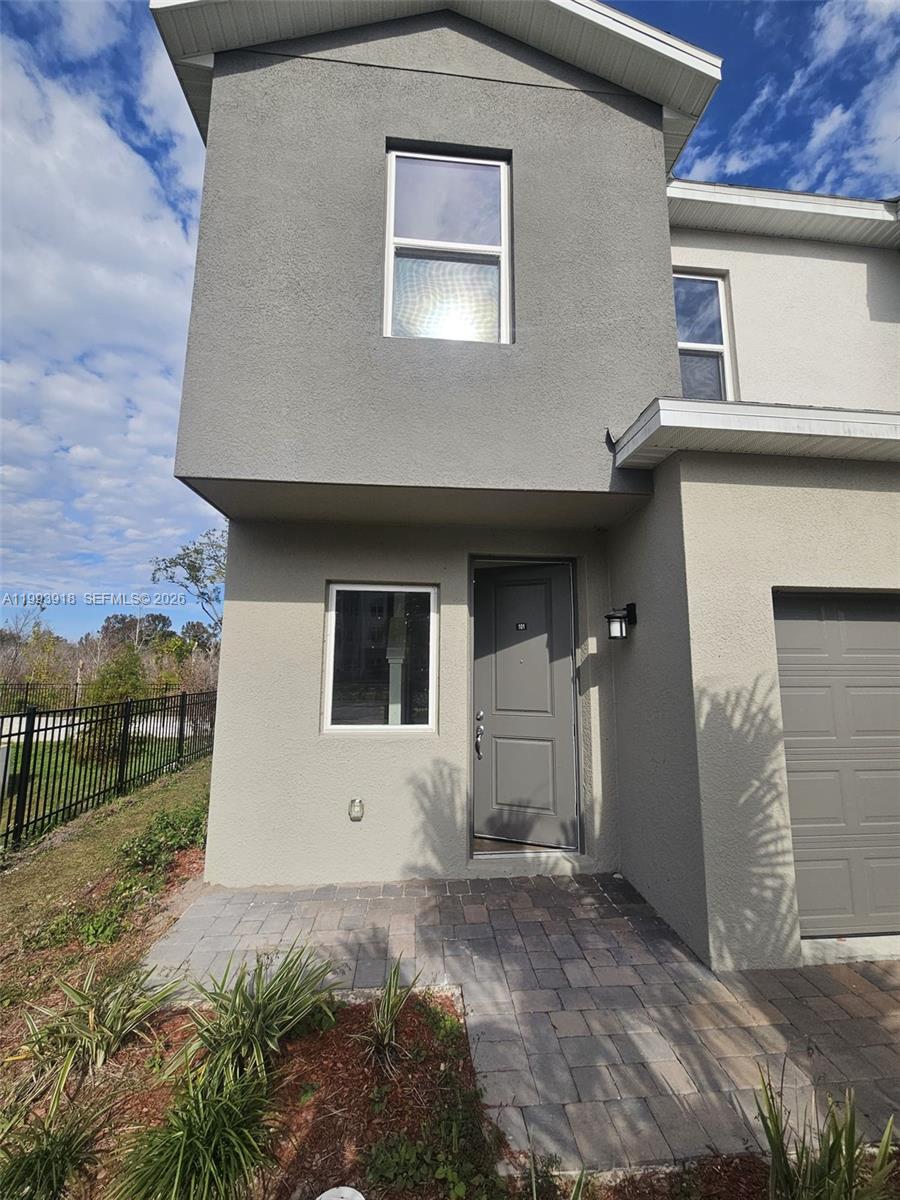A two-story townhouse exterior features a gray stucco facade, a paved walkway, and a garage — 1201 SOUTHSTATION PL # 101, Orlando FL 32809, ORLANDO, FL
