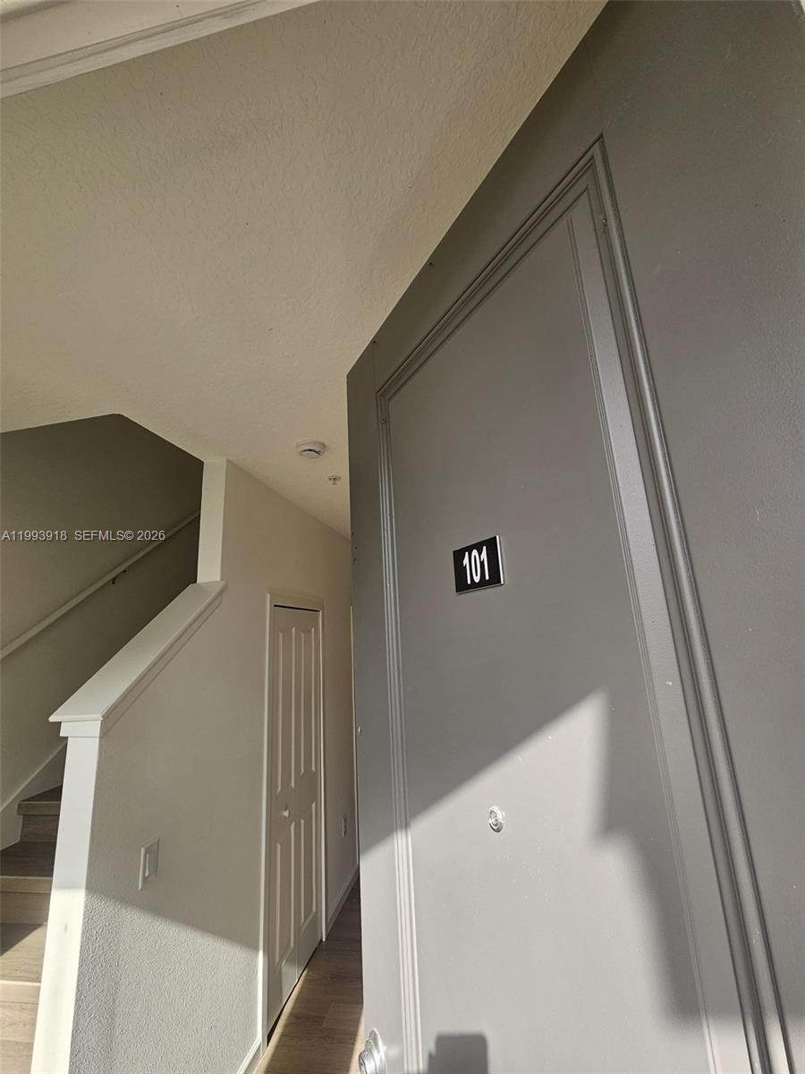 A gray front door labeled 101 stands next to a staircase in an indoor hallway — 1201 SOUTHSTATION PL # 101, Orlando FL 32809, ORLANDO, FL