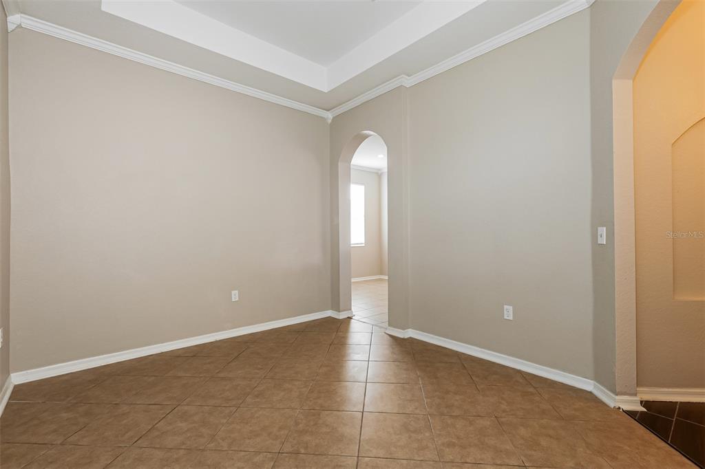 An empty room with tan walls, tile flooring, and an arched doorway leading to another space — 8130 WOODVINE CIRCLE, LAKELAND, FL