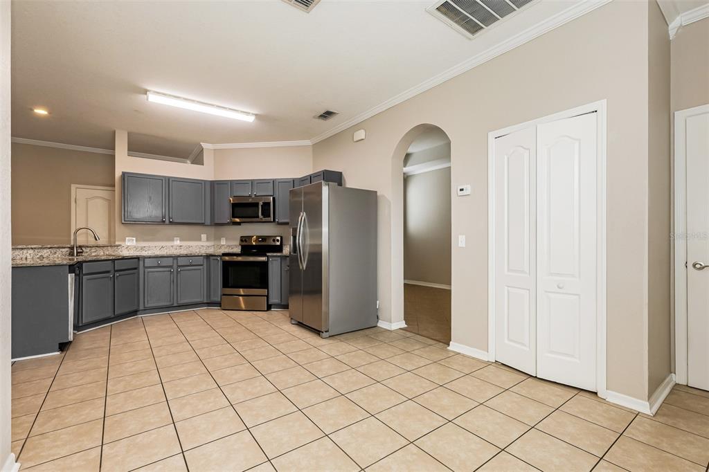 A kitchen with grey cabinets, stainless steel appliances, granite countertops, and light-colored tile flooring — 8130 WOODVINE CIRCLE, LAKELAND, FL
