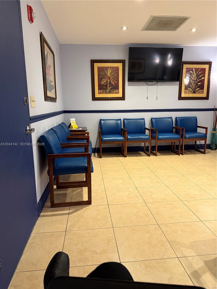 A waiting room features blue chairs, framed palm tree art, and a wall-mounted television — 11801 SW 90th St # 101, Miami FL 33186, MIAMI, FL