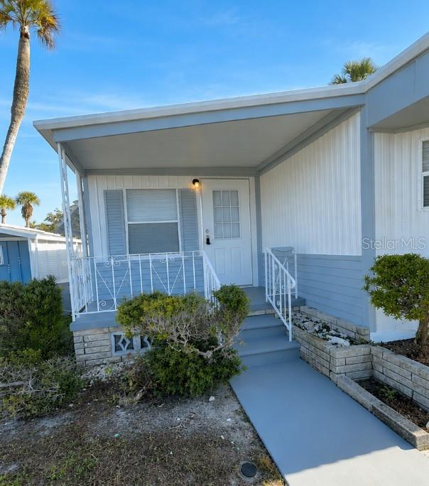 The exterior of a light blue mobile home features a covered porch and concrete steps — 4851 W GANDY BOULEVARD UNIT B7L27, TAMPA, FL
