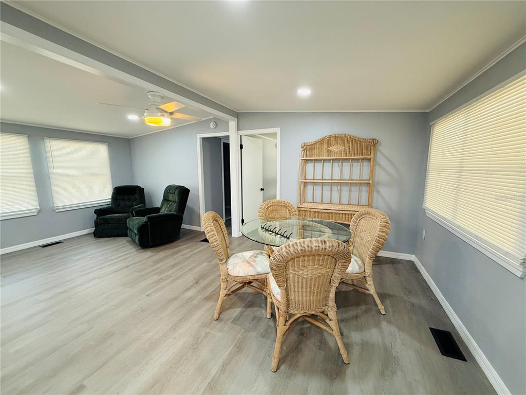 A dining area with a wicker table set and hutch sits beside a living space — 4851 W GANDY BOULEVARD UNIT B7L27, TAMPA, FL