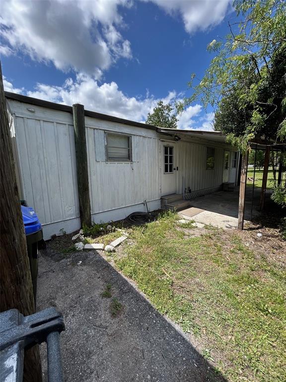 The exterior of a white mobile home features a side entrance and a concrete patio — 3414 DOCTOR LOVE ROAD UNIT C, ORLANDO, FL