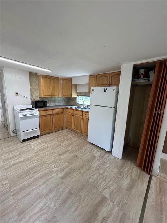 A kitchen features wood cabinets, a white stove, a white refrigerator, and tiled flooring — 3414 DOCTOR LOVE ROAD UNIT C, ORLANDO, FL