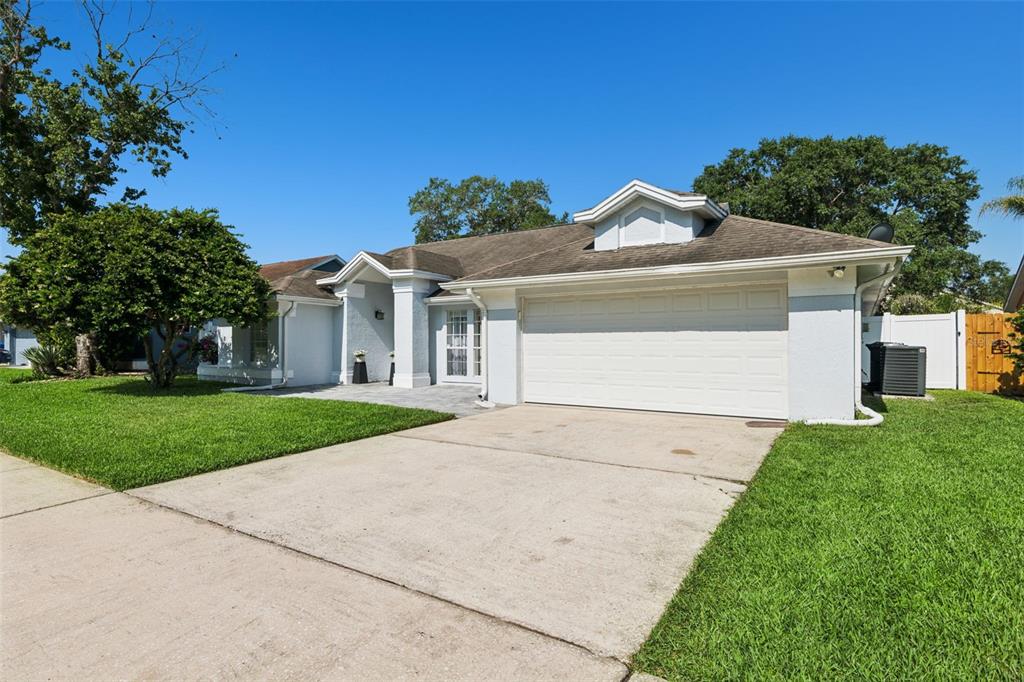 A single-story house with a white stucco exterior, a two-car garage, and a front lawn — 1017 TURTLE CREEK DRIVE, OVIEDO, FL