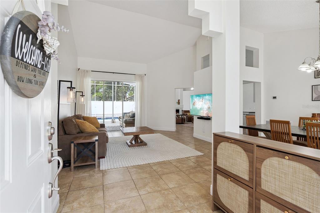 A bright living room with tile floors, a vaulted ceiling, and a view of a pool — 1017 TURTLE CREEK DRIVE, OVIEDO, FL