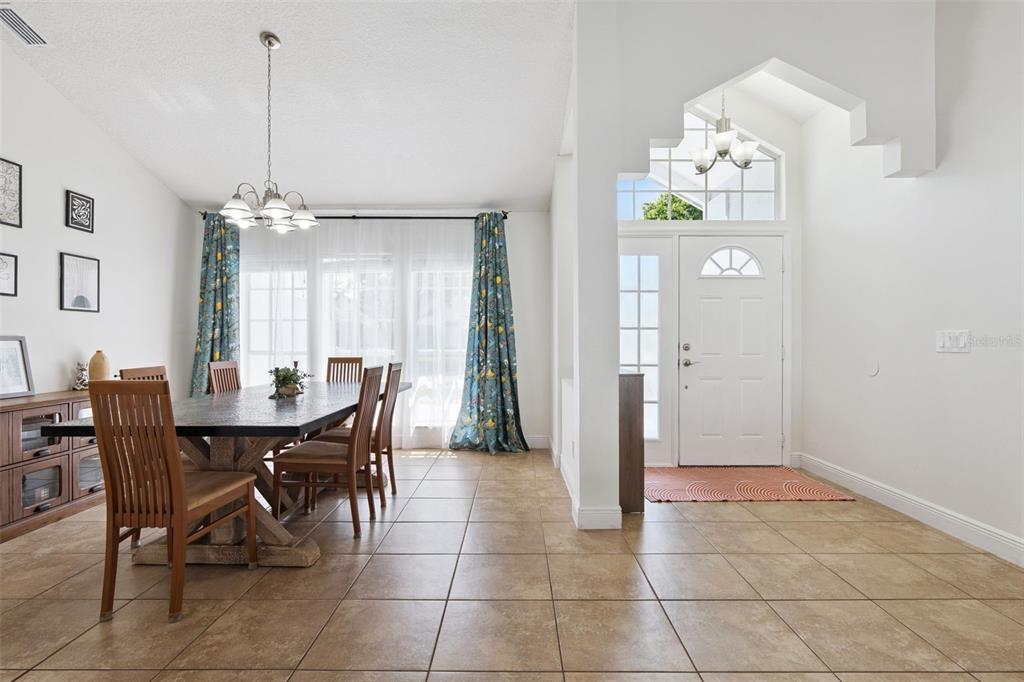 A dining room with tile floors and a chandelier sits next to an entryway — 1017 TURTLE CREEK DRIVE, OVIEDO, FL