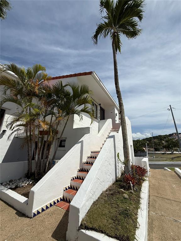A white stucco building exterior features an outdoor staircase with decorative tile accents and palm trees — Cluster 2 6000 RIO MAR BOULEVARD UNIT 5D, RIO GRANDE, PR