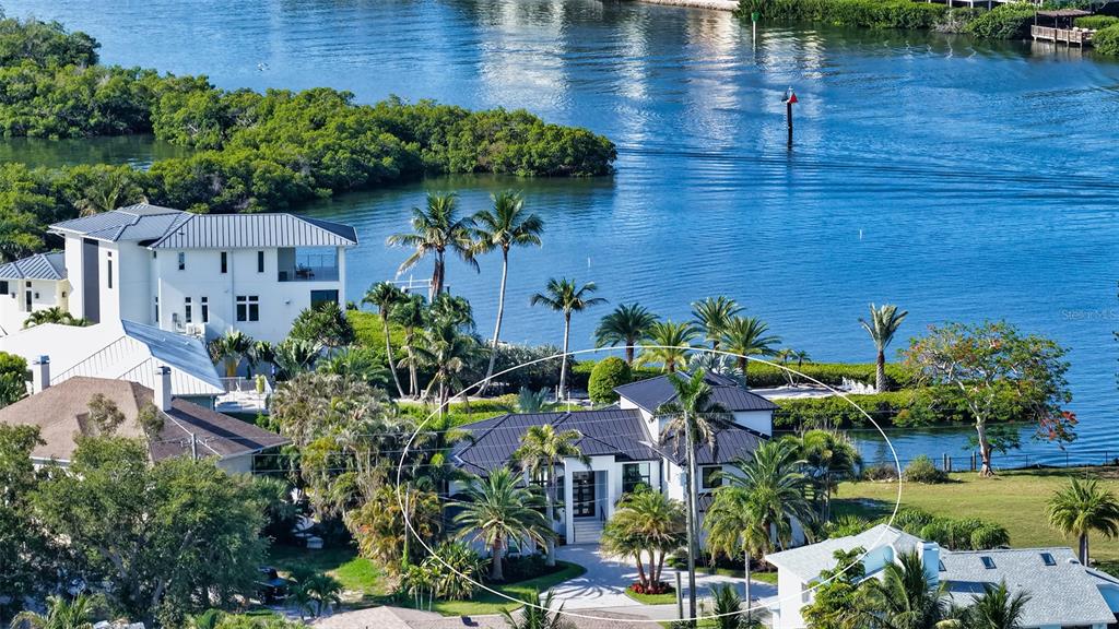An aerial view shows a modern white house with a dark metal roof near water — 1516 RIDGEWOOD LANE, SARASOTA, FL