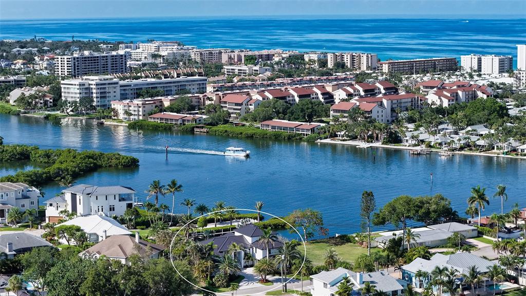 An aerial view shows a waterfront house with a dark roof surrounded by palm trees — 1516 RIDGEWOOD LANE, SARASOTA, FL