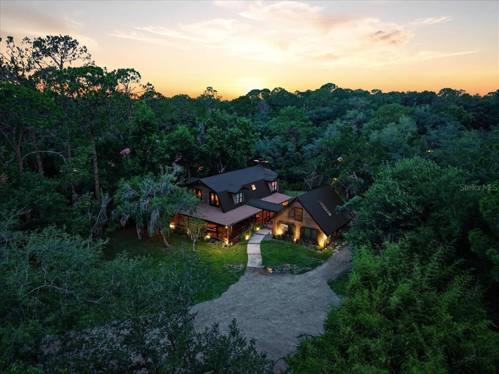 A two-story wooden cabin with a large porch and attached garage at sunset — 1630 STILLMEADOW ROAD, DELTONA, FL