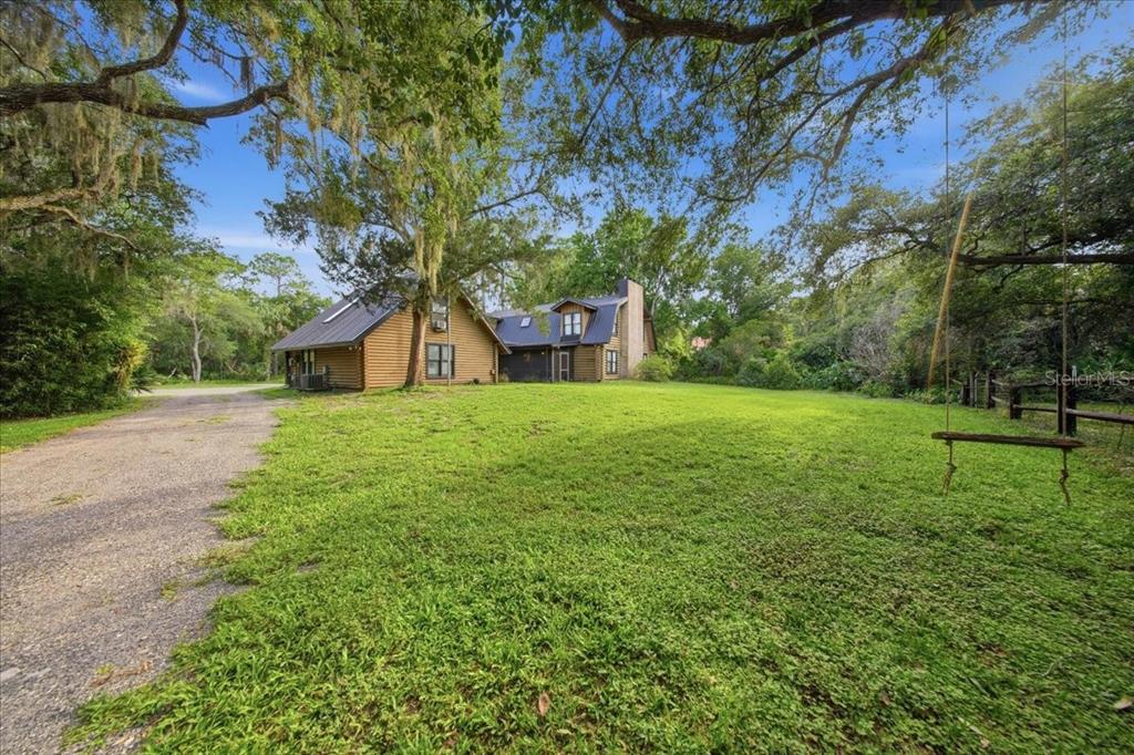 An aerial view of a two-story house with a dark metal roof nestled in trees — 1630 STILLMEADOW ROAD, DELTONA, FL