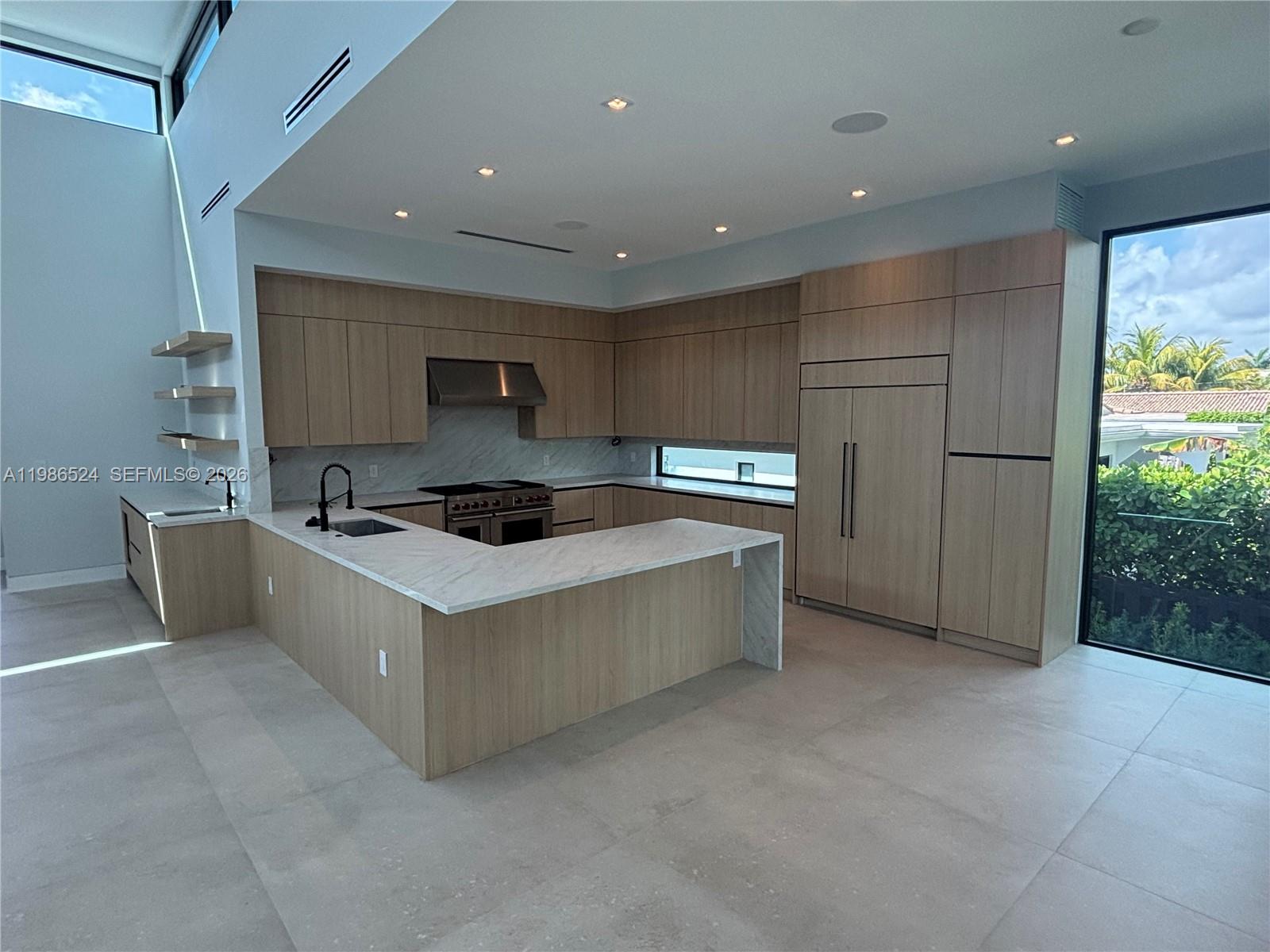 A modern kitchen features light wood cabinetry, white marble countertops, and large floor-to-ceiling windows — 2161 NE 124th St, North Miami FL 33181, NORTH MIAMI, FL