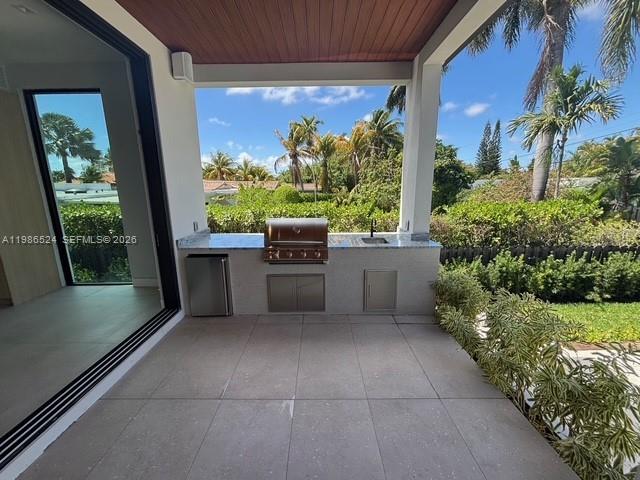 A covered outdoor patio features a built-in grill, stainless steel cabinets, and large tile flooring — 2161 NE 124th St, North Miami FL 33181, NORTH MIAMI, FL