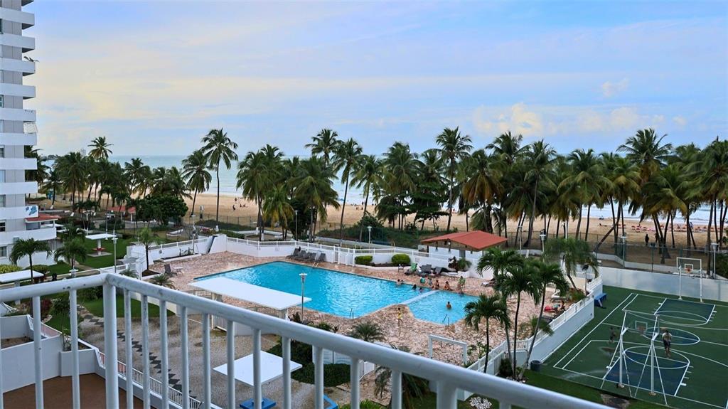 An elevated view of a swimming pool, tennis court, and palm trees near a beach — MARBELLA DEL CARIBE ESTE UNIT 508, CAROLINA, PR