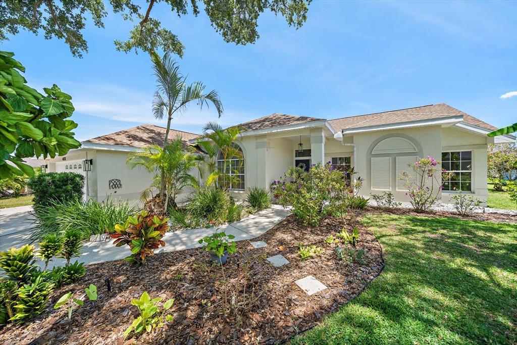 A single-story house with a beige stucco exterior, a tiled roof, and a landscaped front yard — 4732 MEADOWVIEW CIRCLE, SARASOTA, FL