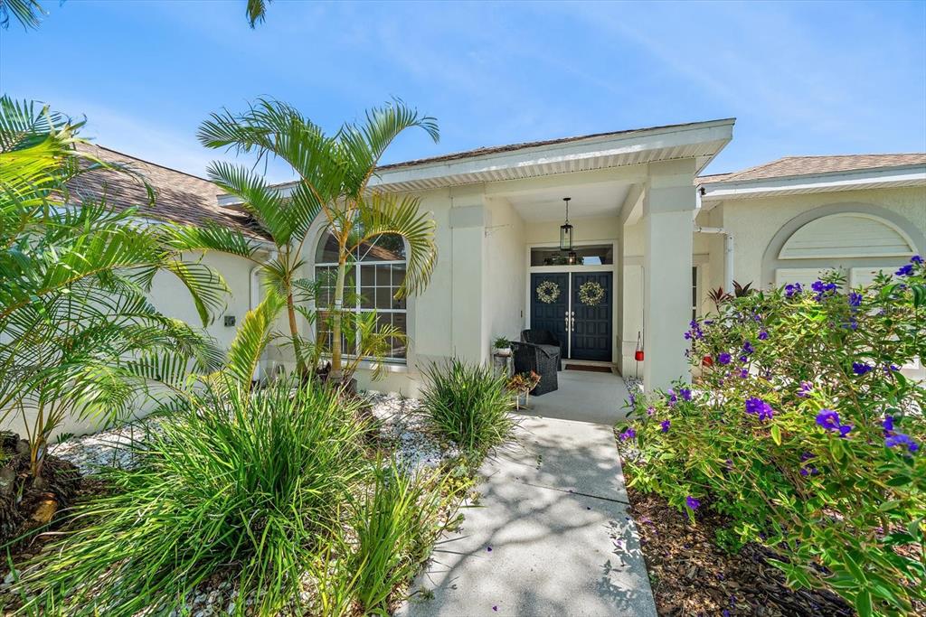 A concrete walkway leads to the covered front entrance of a house with landscaping — 4732 MEADOWVIEW CIRCLE, SARASOTA, FL